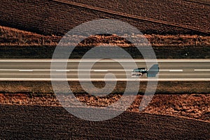 Aerial view of car with towing hauler trailer on road through countryside, top down drone photo