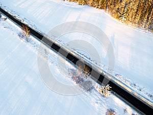 Aerial view of a car on winter road in the forest. Winter landscape countryside. Aerial photography of snowy forest with a car on