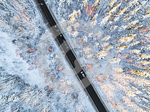 Aerial view of a car on winter road in the forest. Winter landscape countryside. Aerial photography of snowy forest with a car on