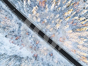 Aerial view of a car on winter road in the forest. Winter landscape countryside. Aerial photography of snowy forest with a car on