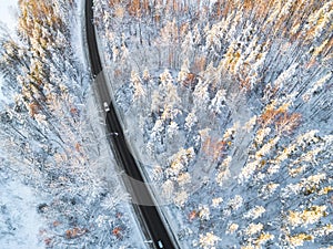 Aerial view of a car on winter road in the forest. Winter landscape countryside. Aerial photography of snowy forest with a car on