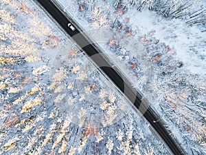 Aerial view of a car on winter road in the forest. Winter landscape countryside. Aerial photography of snowy forest with a car on