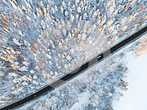 Aerial view of a car on winter road in the forest. Winter landscape countryside. Aerial photography of snowy forest with a car on