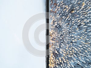 Aerial view of a car on winter road in the forest. Winter landscape countryside. Aerial photography of snowy forest with a car on