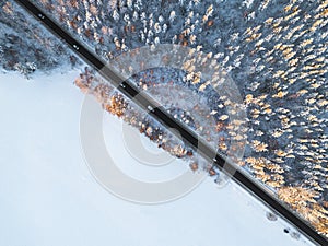 Aerial view of a car on winter road in the forest. Winter landscape countryside. Aerial photography of snowy forest with a car on