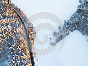 Aerial view of a car on winter road in the forest. Winter landscape countryside. Aerial photography of snowy forest with a car on