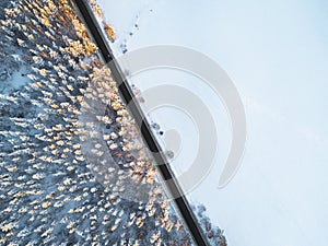 Aerial view of a car on winter road in the forest. Winter landscape countryside. Aerial photography of snowy forest with a car on