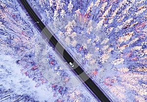 Aerial view of a car on winter road in the forest. Winter landscape countryside. Aerial photography of snowy forest with a car on