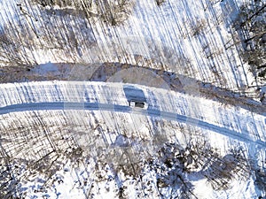 Aerial view of a car on winter road in the forest. Winter landscape countryside. Aerial photography of snowy forest with a car onA
