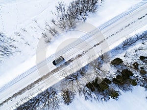 Aerial view of a car on winter road. Winter landscape countryside. Aerial photography of snowy forest with a car on the road.