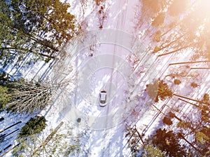 Aerial view of a car on winter road. Winter landscape countryside. Aerial photography of snowy forest with a car on the road. Capt