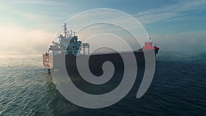 Aerial view of cargo container  ship sails in sea fog, crane vessel working for delivery of delivery containers