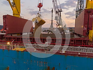 Aerial view of cargo ship bulk carrier is loaded with grain of wheat in port at sunset