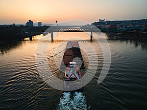 Aerial view of a cargo ship sailing on the Danube through Bratislava. The Danube river and passage under river bridges.