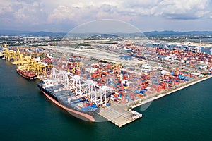 Aerial view of cargo ships loading containers at seaport.