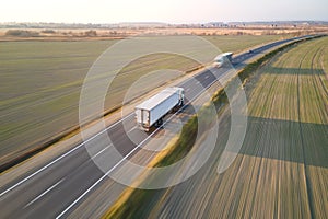 Aerial view of cargo trucks driving on highway hauling goods. Delivery transportation and logistics concept