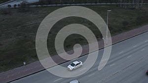 Aerial view of cars on highway. Stock footage. Multi lane motorways with driving vehicles along green summer meadow.