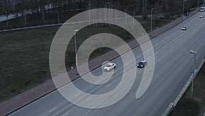Aerial view of cars on highway. Stock footage. Multi lane motorways with driving vehicles along green summer meadow.