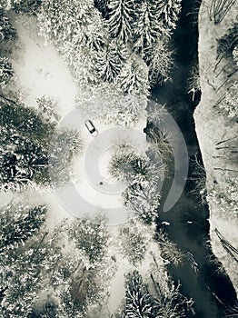 Aerial view of cars riding on the snowy country road, near the dark blue river, through the beautiful snow covered