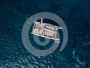 Aerial view of a catamaran with person on board and in the sea swimming. island of Lanzarote, Canary, Spain.
