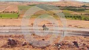 Aerial view caucasian male person solo cycle bicycle touring in countryside fully loaded with bags outdoors