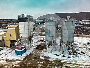 Aerial view of cement factory tower with high concrete plant structure at industrial production area at sunset. Manufacturing and