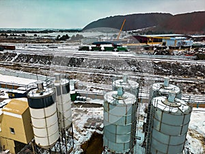 Aerial view of cement factory tower with high concrete plant structure at industrial production area at sunset. Manufacturing and