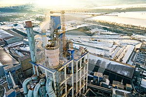Aerial view of cement plant with high factory structure and tower crane at industrial production area