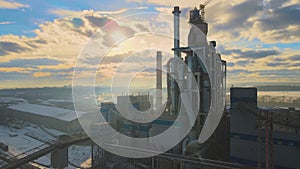 Aerial view of cement plant with high factory structure and tower crane at industrial production area.