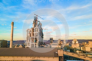 Aerial view of cement plant with high factory structure and tower crane at industrial production area