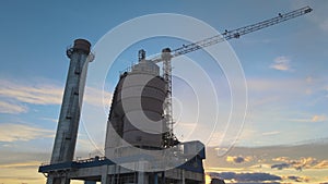 Aerial view of cement plant with high factory structure and tower crane at industrial production area.