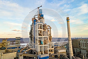 Aerial view of cement plant with high factory structure and tower crane at industrial production area