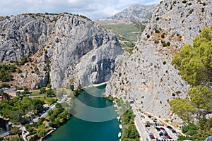Aerial view of Cetina river near Omis, Croatia with green waters and tall rock walls, on blue sky Summer day. Tourism