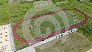 Aerial view children play football on a small football field. Modern football ground near the school
