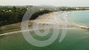 Aerial view of children in white uniforms playing near sea at dusk. School kids enjoy summer camp activities on sandy