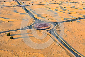 Aerial view of circle roundabout, half desert road or street with sand dune in Dubai City, United Arab Emirates or UAE. Natural