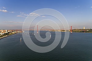 Aerial view of the city of Lisbon with sailboats on the Tagus River and the 25 of April Bridge on the background;