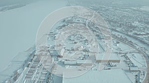 Aerial view of the city residential buildings and a river in winter, urban winter landscape. Clip. Snow covered city in