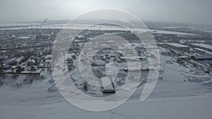 Aerial view of the city residential buildings and a river in winter, urban winter landscape. Clip. Snow covered city in