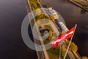 Aerial view of a cityscape with a river and the flag of Austria floating in the sky