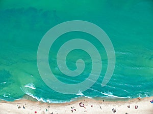 Aerial view on a clean sand beach and blue ocean with sunbathers