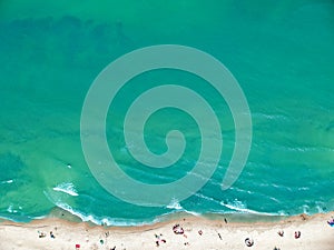 Aerial view on a clean sand beach and blue ocean with sunbathers photo