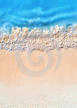 Aerial view of clear blue sea with waves and empty sandy beach