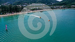 Aerial view of clear sea water with boats and tourists enjoying the beach in Patong beach, Phuket island, Thailand.