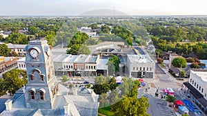 Aerial view close-up Clock Tower of Hood County Courthouse and lush green neighborhood in Granbury, Texas, USA