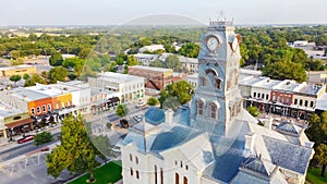 Aerial view close-up Clock Tower of Hood County Courthouse and lush green neighborhood in Granbury, Texas, USA