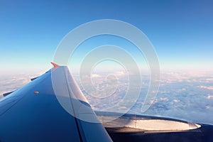 Aerial view of cloud blue sky and plane wing view through the airplane window