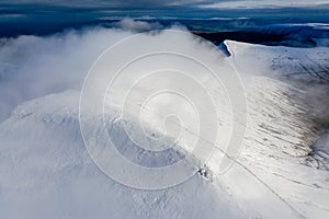 Aerial view of clouds moving over the summit of snow capped mountains