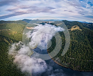 Aerial view clouds over the forest and lake at sunrise. View from drone. Aerial top view cloudscape. Transylvania, Romania