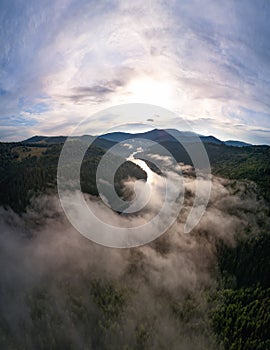 Aerial view clouds over the forest and lake at sunrise. View from drone. Aerial top view cloudscape. Transylvania, Romania